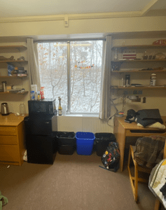 A view of one side of Felix's dorm room, showing a window, 2 desks, and bookshelves.